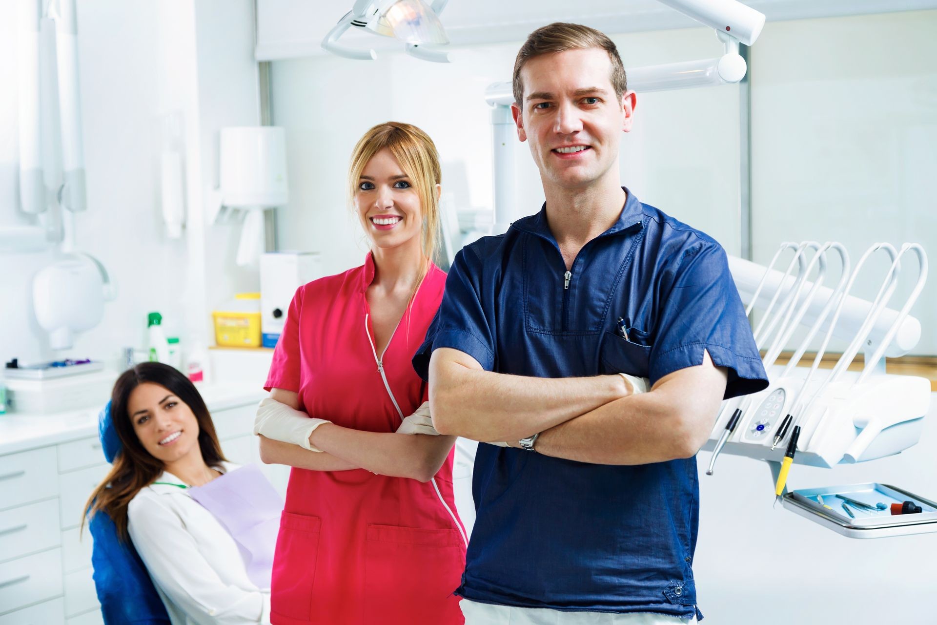 Portrait of two young dentists with the patient looking at camera while standing in a dental clinic.